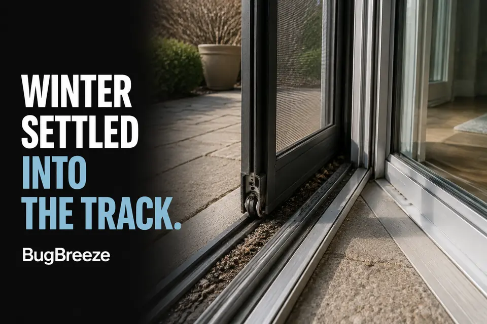 Winter grit, salt residue, and compacted debris collected in an aluminum sliding screen-door track.